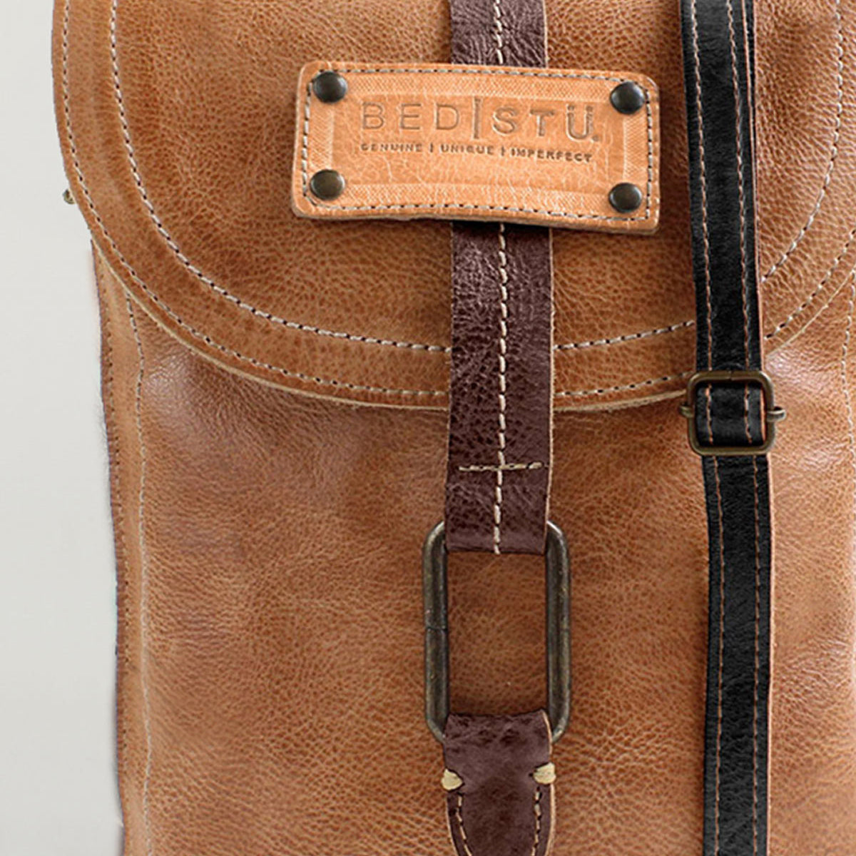Close-up of the Studio Ring Strap, a brown leather customizable bag by Bed|Stü, featuring a stitched label reading "Bed|Stü" and a front strap with a metal buckle.