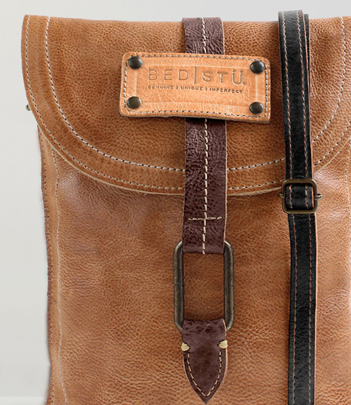 Close-up of the Studio Ring Strap, a brown leather customizable bag by Bed|Stü, featuring a stitched label reading "Bed|Stü" and a front strap with a metal buckle.