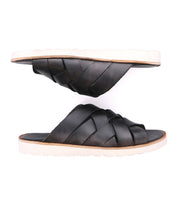 The Bed|Stü Abraham Light is a pair of black slide sandals with a woven leather upper and white soles designed for all-day comfort, pictured from the side on a white background.