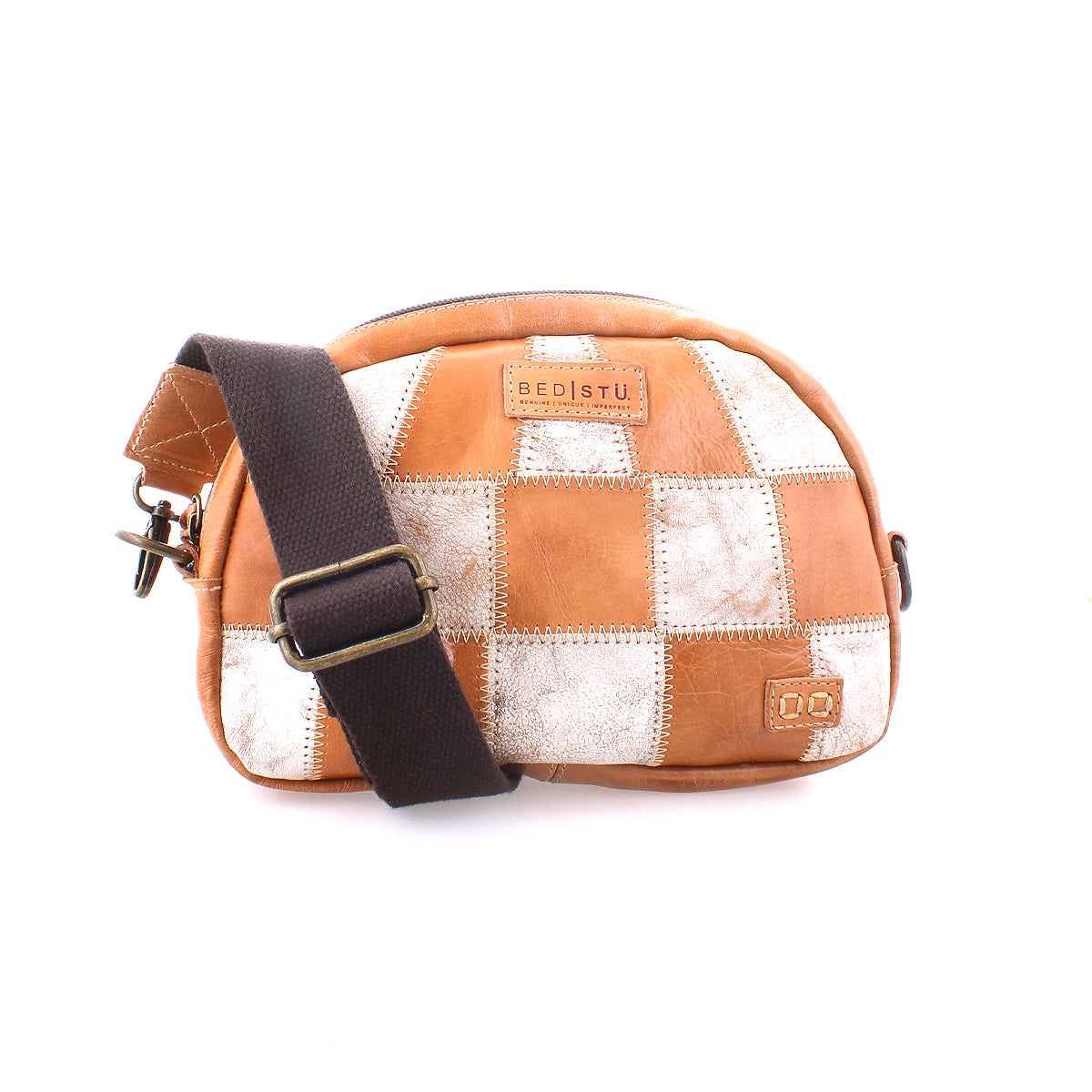 The Bed|Stü Abundance is a small crossbody bag crafted from reclaimed leather, showcasing a brown and white patchwork design and finished with a dark adjustable fabric strap, all set against a white background for an eco-friendly, stylish appearance.