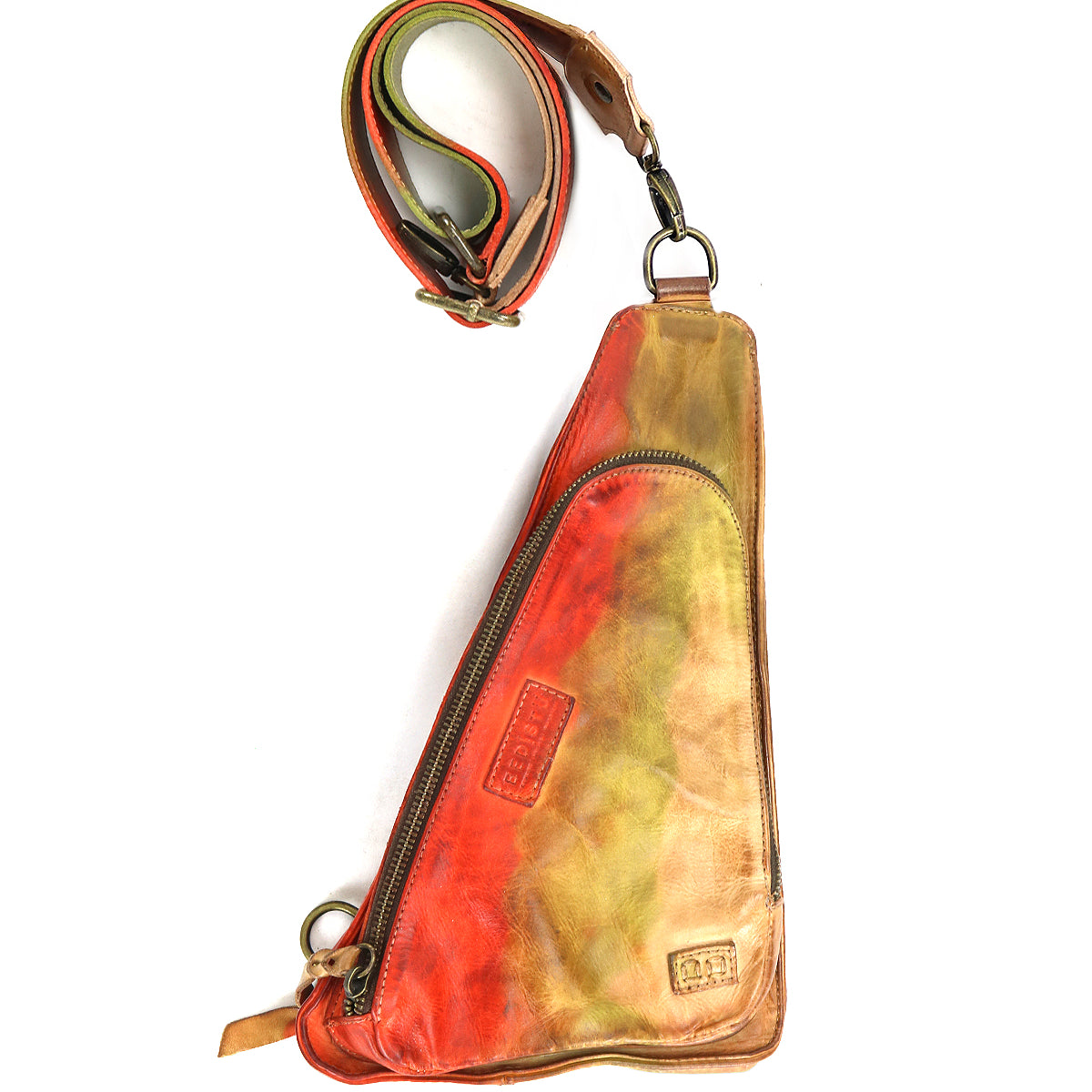 Introducing the Adept by Bed|Stü: a triangular crossbody crafted from vegetable-tanned leather in a striking red, green, and tan gradient. This compact sling features a front zipper and comes with a matching adjustable strap laid above the bag, making it perfect for carrying your everyday essentials.