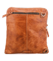 The Bed|Stü Aiken is a brown full-grain leather crossbody bag with a front zipper pocket, decorative stitching, and metal hardware on the corners. It features an adjustable strap for comfort and is photographed on a white background.