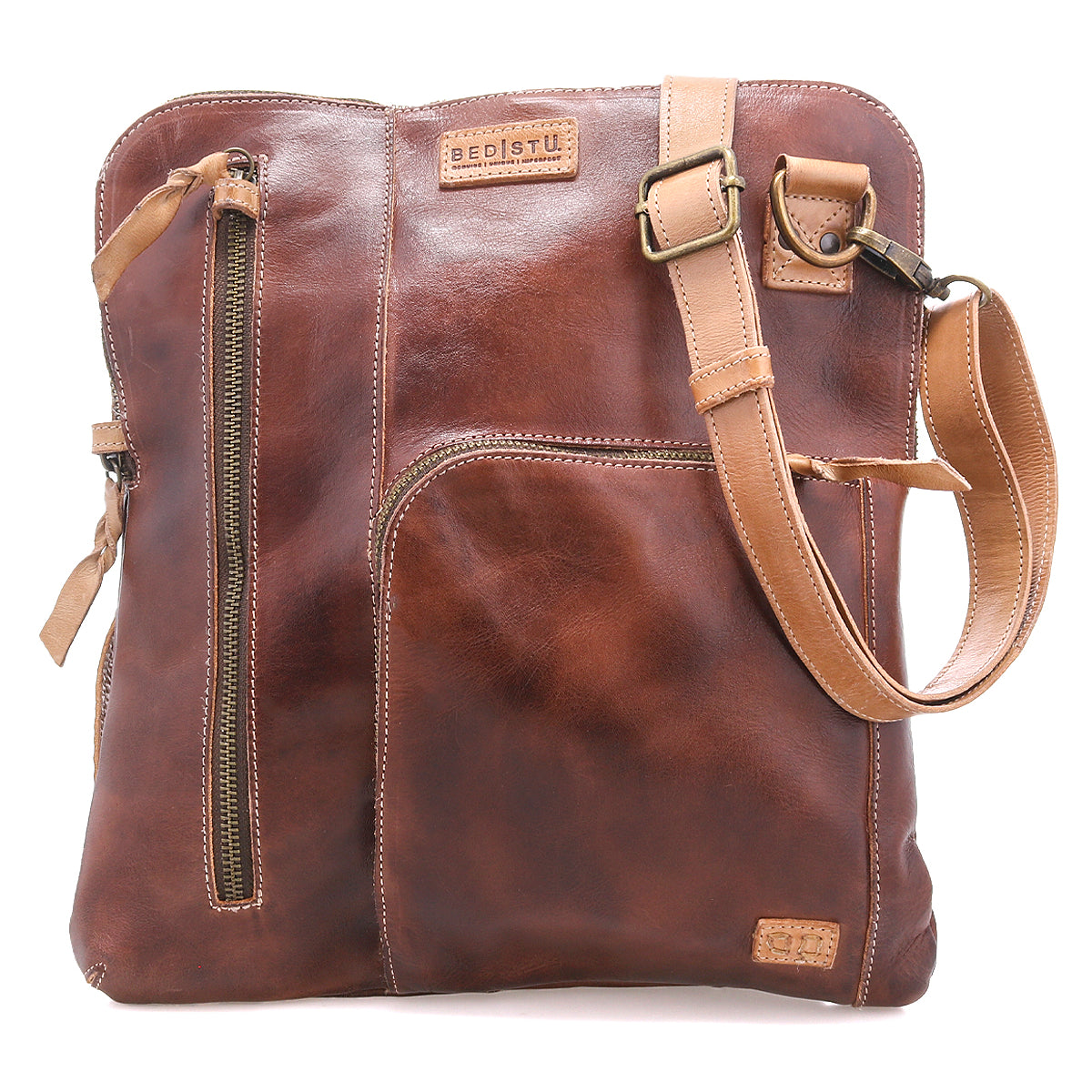 The Aiken by Bed|Stü is a brown full-grain leather crossbody bag featuring an adjustable strap, anti-theft security features, multiple zippered pockets, and embossed branding on the upper front.