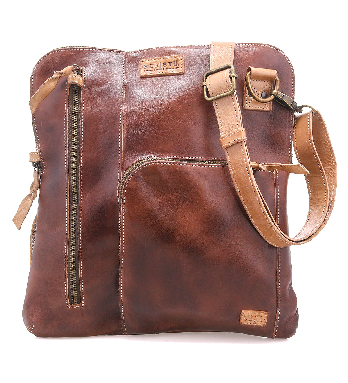 The Aiken by Bed|Stü is a brown full-grain leather crossbody bag featuring an adjustable strap, anti-theft security features, multiple zippered pockets, and embossed branding on the upper front.