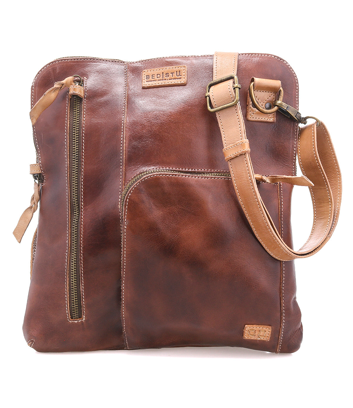 The Aiken by Bed|Stü is a brown full-grain leather crossbody bag featuring an adjustable strap, anti-theft security features, multiple zippered pockets, and embossed branding on the upper front.