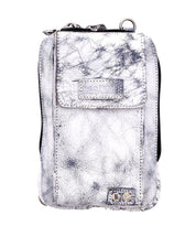 Meet Alelike by Bed|Stü—a small pouch in a silver-gray textured finish, featuring a front flap pocket, top zipper closure, and a metal ring on one corner. It’s the perfect stylish companion for carrying your travel essentials.