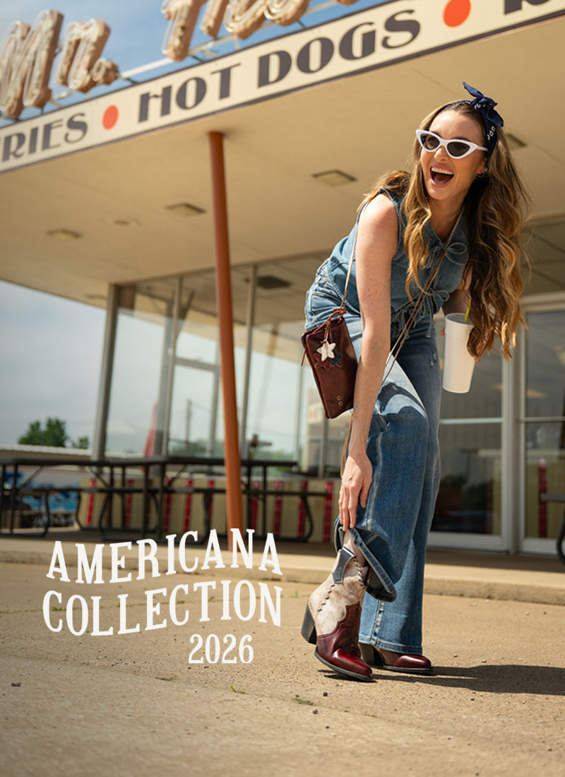 Woman in denim and white sunglasses laughing outside a retro hot dog stand while adjusting a red-and-white western boot, with “Americana Collection 2026” text overlaid.