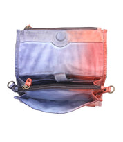 The Amina crossbody purse by Bed|Stü is a small, open bag with a blue and red gradient. It features multiple compartments—including a main section, zippered pocket, and side pockets—with visible stitching and a magnetic snap closure.