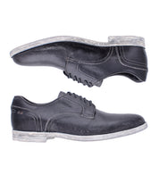 Two Bed|Stü Anchiano black oxford shoes with white stitching and worn, light-colored soles, crafted from distressed leather and displayed side by side on a white background.