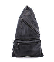 Bed|Stü's Andie black leather sling bag, featuring three zippered compartments and an adjustable strap, is pictured standing upright against a white background.