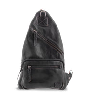 Introducing the Andie by Bed|Stü: a black leather sling bag featuring two zippered front pockets, a small branded patch at the bottom, an adjustable strap for personalized comfort, and a convenient top handle for easy carrying.