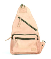 The Bed|Stü Andie is a light pink leather sling bag featuring two zippered compartments, a small front pocket, and an adjustable strap, displayed against a white background.