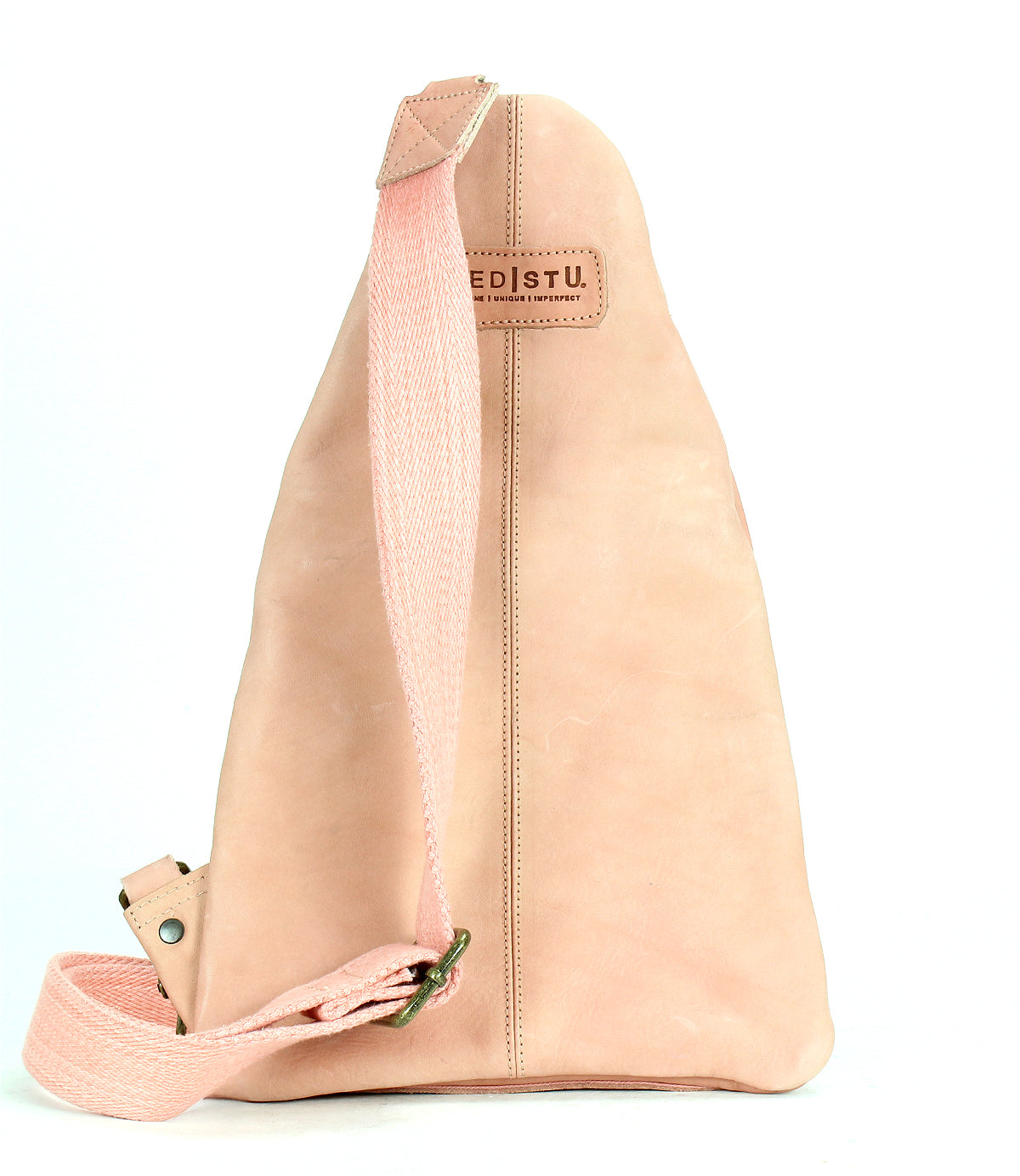 Light pink leather sling bag called "Andie" by Bed|Stü, featuring an adjustable sturdy fabric strap, vertical stitching details, and a rectangular "Bed|Stü" patch on the front, photographed against a white background.