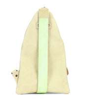 The Andie triangular sling bag by Bed|Stü is shown from the back against a plain white background, featuring a beige body and a single light green adjustable strap.