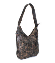 The Bed|Stü Argus is a brown distressed handcrafted leather shoulder bag featuring a large main compartment, a slanted front zippered pocket, and a wide strap, shown against a white background.