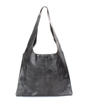 The Ariel II by Bed|Stü is a large black leather tote bag featuring a wide strap, a rectangular body, simple stitching, and a slightly glossy finish, beautifully displayed on a white background. This spacious tote combines style and functionality, making it ideal for everyday use.