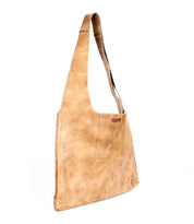 The Ariel II by Bed|Stü is a tan leather crossbody bag with a wide shoulder strap and visible stitching, standing upright against a white background—a lightweight tote designed for effortless everyday use.