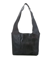 The Ariel Mid by Bed|Stü is a black artisanal shoulder bag made from vegetable-tanned leather, featuring a wide strap, front stitching details, and a rectangular logo patch on the upper front center.