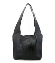 The Ariel Mid by Bed|Stü, an artisanal black shoulder bag crafted from vegetable-tanned leather with wide straps and a rectangular silhouette, is displayed upright against a white background.