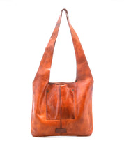 The Ariel Mid by Bed|Stü is an artisanal brown shoulder bag crafted from vegetable-tanned leather, featuring a single wide strap, two front pockets, and visible stitching, displayed against a white background.
