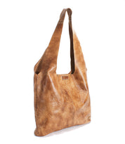 The Ariel EM by Bed|Stü is a large brown leather shoulder bag with embossed floral patterns, designed as a limited edition tote featuring a wide strap and a soft, slouchy structure, displayed here against a white background.