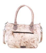 Introducing the Astana by Bed|Stü, a beige and brown marbled modern handbag inspired by classic vintage bowling bag style. It features two sturdy handles, a front zip pocket, detachable shoulder strap, and striking metal hardware. Photographed on a white background, the Astana is the perfect everyday bag.