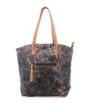 Barra II by Bed|Stü is a brown leather handcrafted tote bag featuring two tan shoulder straps, a front zipper pocket, and convenient organizational compartments. Showcasing a weathered, distressed finish, it is displayed against a white background.