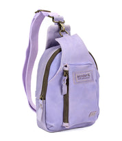 The Beau by Bed|Stü is a compact lavender leather sling backpack featuring a front zip pocket, side pocket, adjustable strap, and a branded "Bed|Stü" patch on the front.