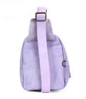 A side view of the Bed|Stü Beau, a light purple leather sling bag featuring a wide adjustable strap with a metal buckle, set against a white background.