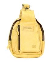 Introducing the Beau by Bed|Stü—a small yellow leather sling bag featuring two zippered compartments and a signature front patch. This compact backpack is ideal for carrying your essentials with stylish ease.