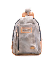 The Beau backpack by Bed|Stü is a small sling bag in gray and brown leather, featuring a front zip pocket, a top handle, and the brand's signature label, shown against a white background.