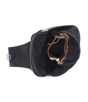 The Beau sling bag by Bed|Stü in black fabric leather features a zipper closure, brown strap, and inner pocket, photographed from above on a white background.