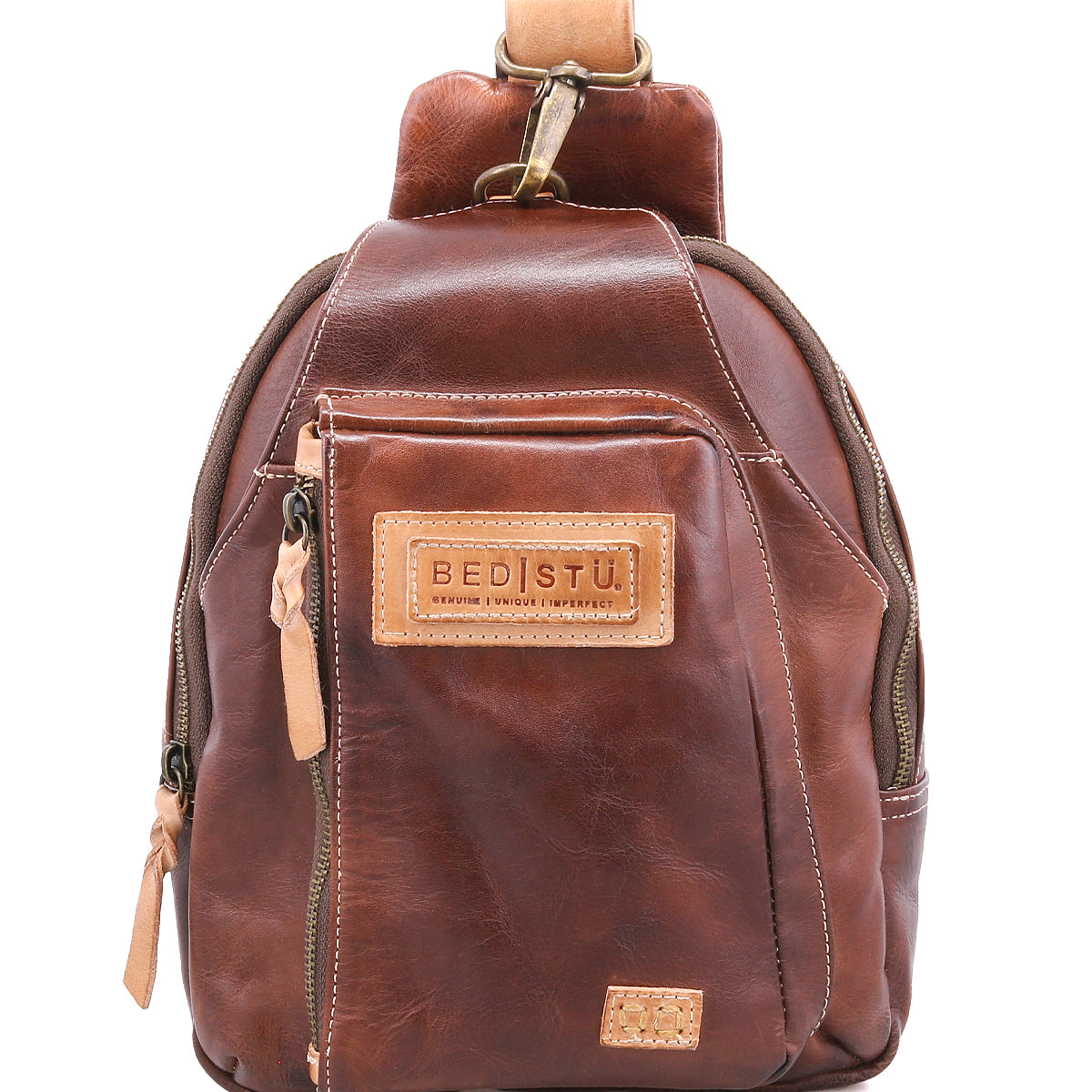 A small brown leather sling backpack called the "Beau" by Bed|Stü, featuring a front zipper pocket, tan leather zipper pulls, and a stitched "BED|STU" label on the front.