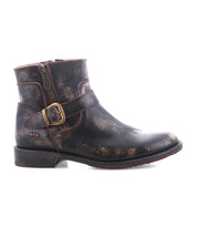 The Bed|Stü Becca is a single distressed black leather ankle engineer boot featuring a side zipper, a decorative ankle buckle, and a low heel, with a sturdy leather shaft; shown in profile against a white background.