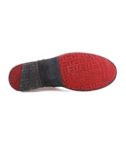 The image displays the bottom view of the Bed|Stü Becca dress shoe, showcasing its red rubber sole with textured patterns and a black heel—details inspired by the sturdy craftsmanship typical of an engineer boot.