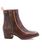 The Bed|Stü Bitsy is a brown leather ankle boot featuring a side zipper, stacked heel, and tan trim, shown against a white background.
