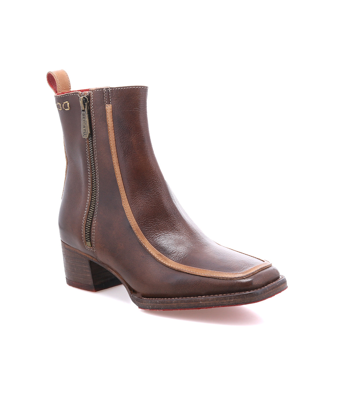 The Bed|Stü Bitsy is a brown leather ankle boot featuring a subtle square toe, side zipper, tan trim, low stacked heel, and a red pull tab—stylishly displayed on a white background.