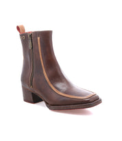 The Bed|Stü Bitsy is a brown leather ankle boot featuring a subtle square toe, side zipper, tan trim, low stacked heel, and a red pull tab—stylishly displayed on a white background.