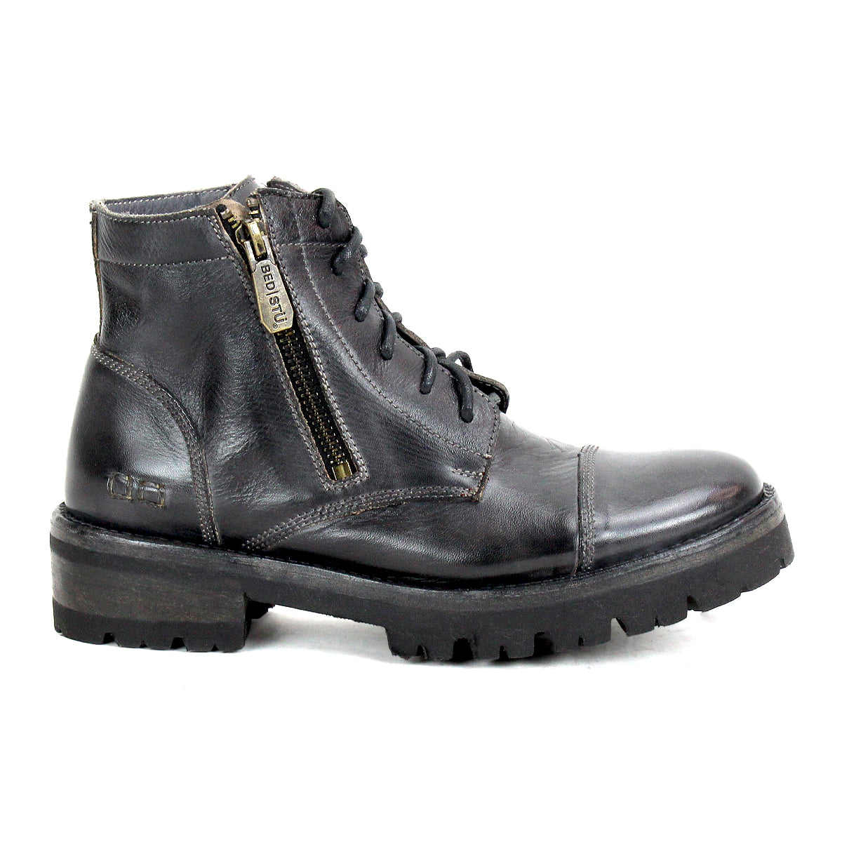 The Bed|Stü Bonnie IV is a black leather combat boot featuring dual side zippers, a lace-up front, and a rugged rubber sole, displayed in a left side profile against a white background.