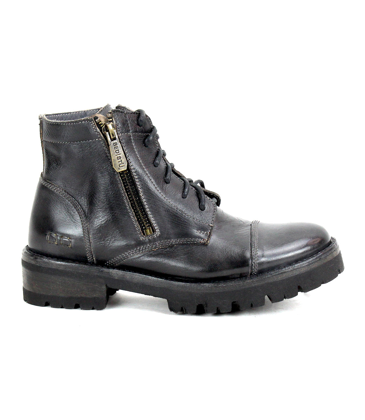 The Bed|Stü Bonnie IV is a black leather combat boot featuring dual side zippers, a lace-up front, and a rugged rubber sole, displayed in a left side profile against a white background.