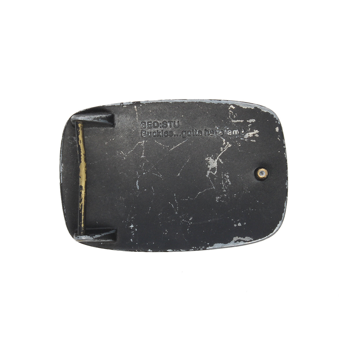 A worn black Bed|Stü 95 Buckle with visible scratches and the text "BEDSTU Buckles... gotta have 'em" rests on a plain white background, capturing the rugged charm of this classic Bed|Stü belt buckle.