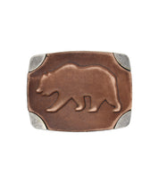 The Bed|Stü Bear Buckle is a rectangular brown antiqued belt buckle, highlighted by a raised bear design at the center and finished with silver-colored metal corners.