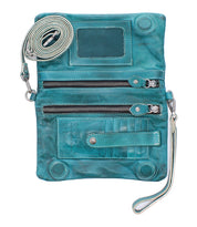 The Cadence by Bed|Stü is a teal, vegetable-tanned leather crossbody bag featuring two zippered compartments, card slots, a clear ID window, and an adjustable strap. Shown open and empty, this versatile clutch combines style and function.