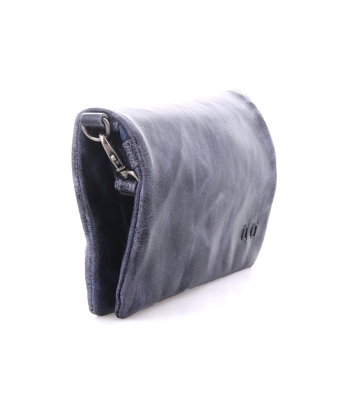 The Bed|Stü Cadence is a dark blue, vegetable-tanned leather pouch featuring a metal clasp, photographed against a white background with the image highlighting its side profile and partially revealing the interior.