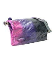 Introducing the Cadence by Bed|Stü: a rectangular crossbody clutch crafted from vegetable-tanned leather, showcasing a striking tie-dye pattern in pink, purple, and black. It features an adjustable strap and a secure metal clasp for added style and function.