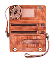 The Cadence crossbody clutch by Bed|Stü, crafted from vegetable-tanned brown leather, features multiple zippered compartments, card slots, a clear ID window, and an attached rolled wrist strap. Shown open on a white background.