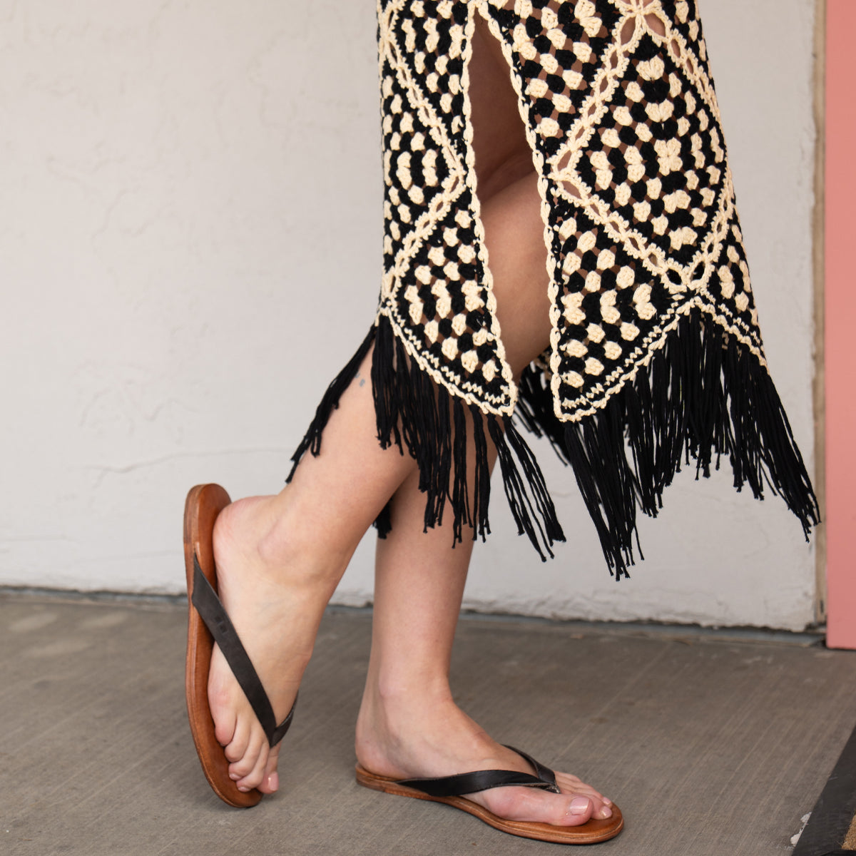 Wearing the Calma lightweight brown leather sandals by Bed|Stü, paired with a black and beige crochet skirt with fringe, standing comfortably on a concrete floor.
