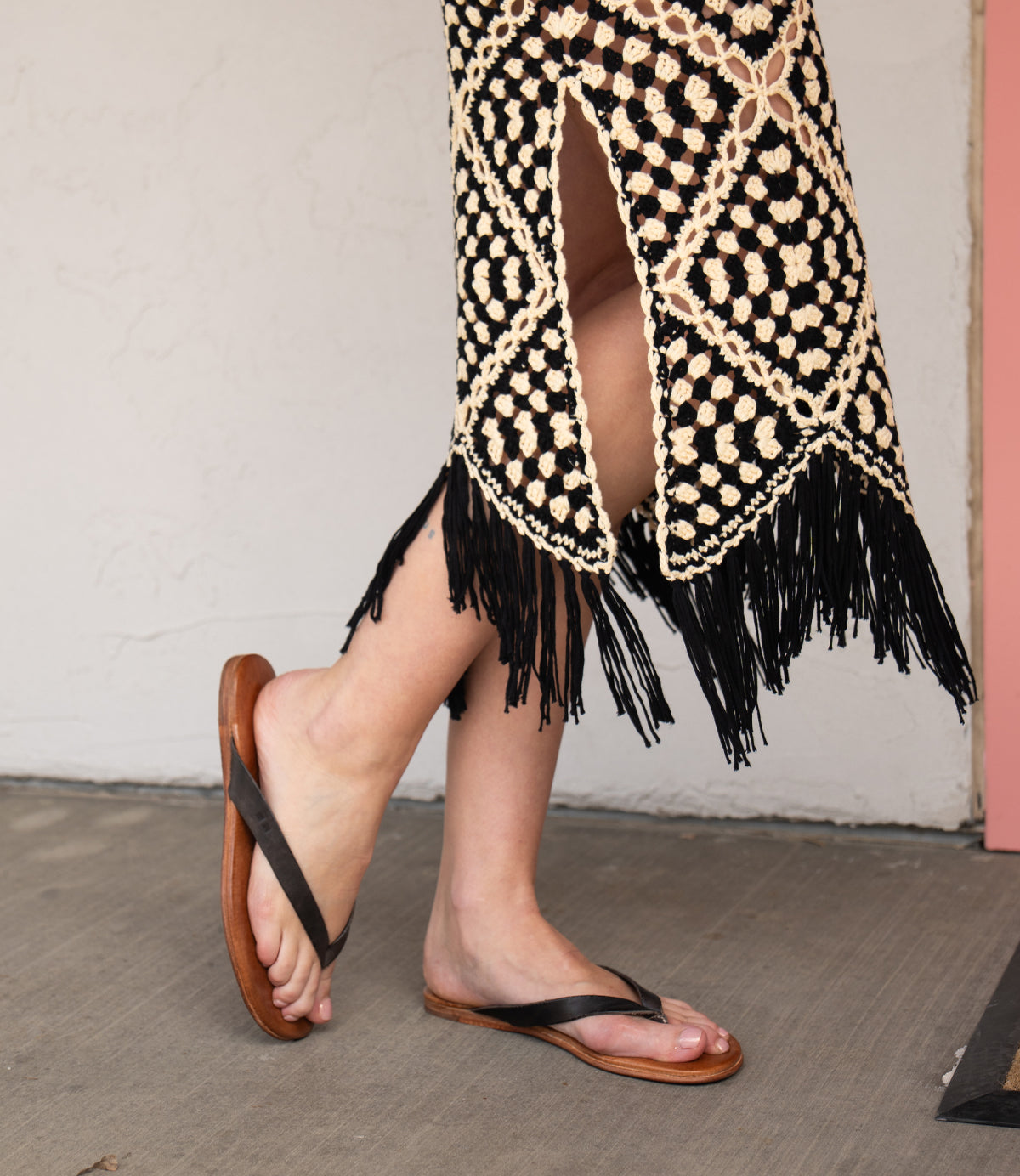 Wearing the Calma lightweight brown leather sandals by Bed|Stü, paired with a black and beige crochet skirt with fringe, standing comfortably on a concrete floor.