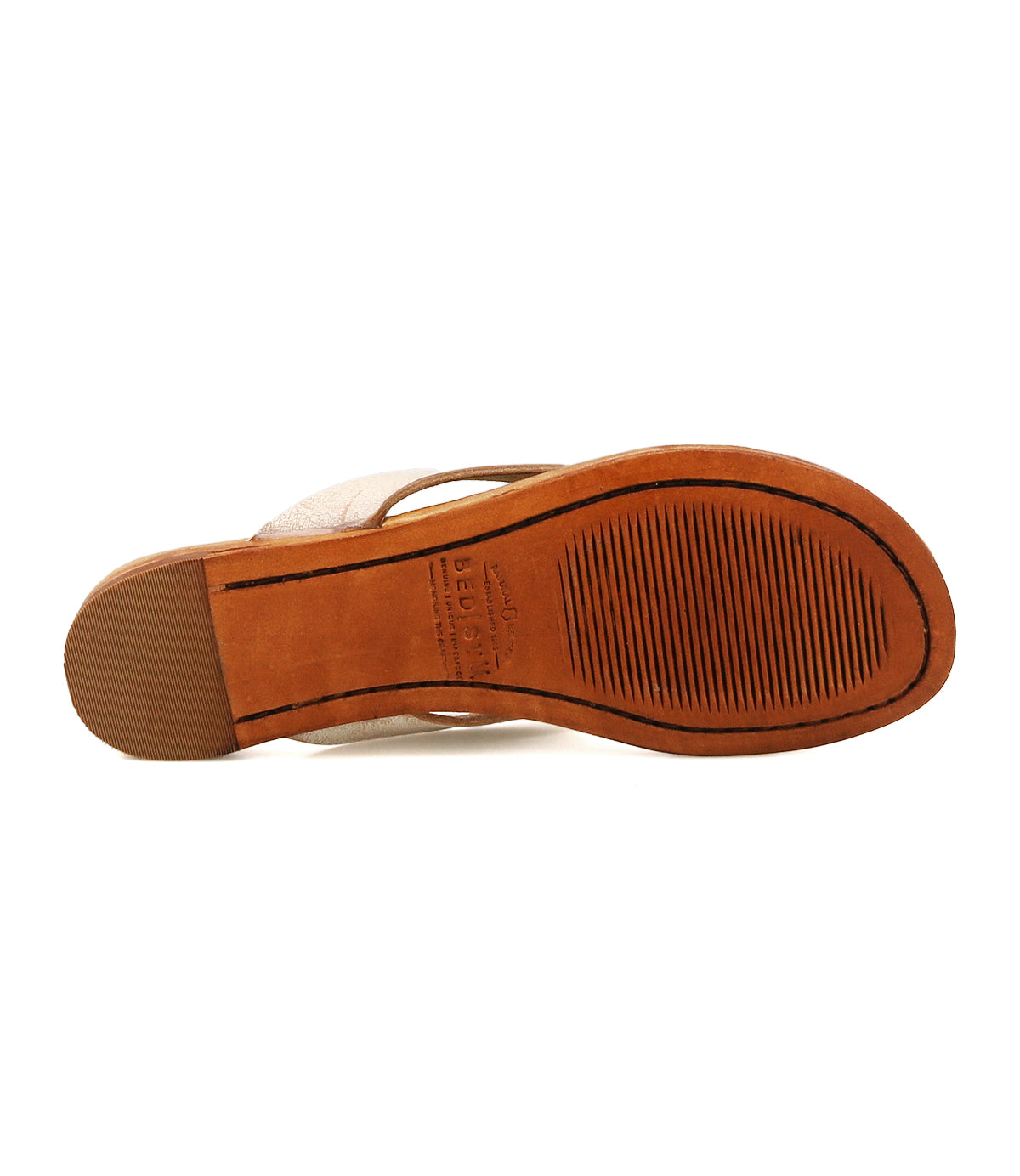 The image displays the bottom view of the Bed|Stü Calma sandal, featuring a brown leather sole with textured grooves and embossed Bed|Stü branding at the center, emphasizing its comfortable and lightweight design.