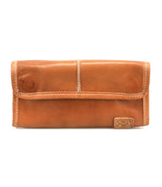 The Canton wallet by Bed|Stü is a tan leather 2-in-1 design featuring visible stitching and a small rectangular patch on the bottom right corner, showcased against a white background for a versatile and stylish look.